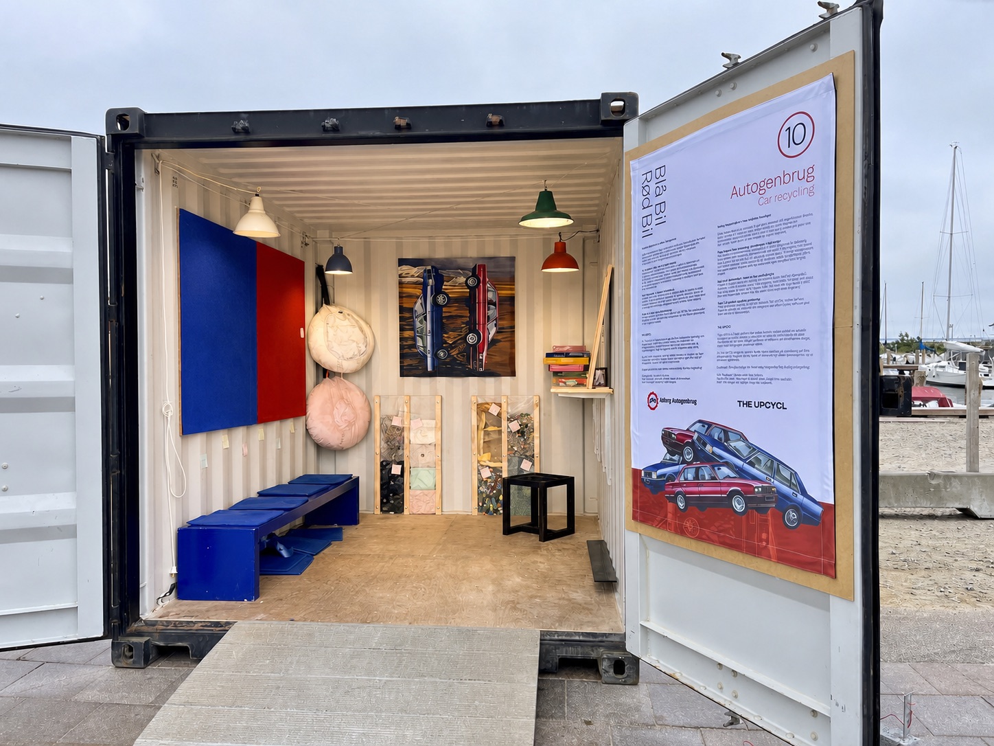 Den oplyste udstillingscontainer med værker af genbrugte bilmaterialer